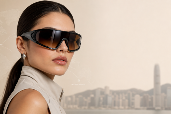 Woman wearing oversized black sunglasses and a beige sleeveless jacket against a beige backdrop with a faint world map overlay and Hong Kong skyline in the distance. | Concept Eyewear OEM Manufacturer