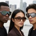 Three models wearing sunglasses on a city rooftop, posing for a fashion shoot with a skyline in the background.