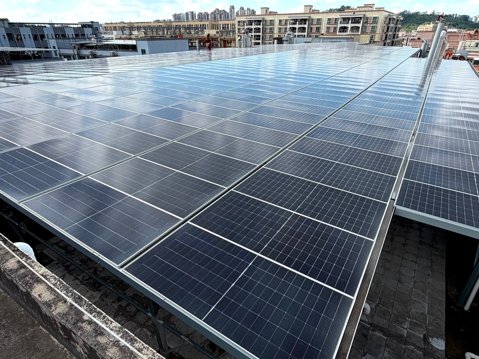 Solar panels installed across a commercial rooftop in an urban area.