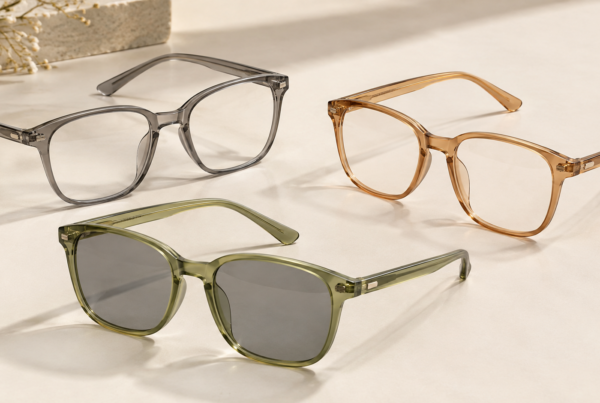 Three translucent soft-square eyewear frames in smoke gray, caramel amber and muted olive, with the olive frame fitted with gray sun lenses.