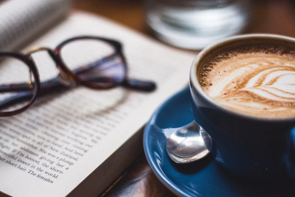 Unbranded eyeglasses on a book beside coffee, illustrating how brands choose eyewear OEM manufacturer partners with editorial care