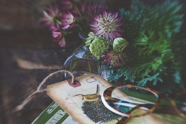 Eyewear assortment merchandising calendar: unbranded tortoiseshell optical frames with seasonal floral styling on wood, planning editorial, no brand marks