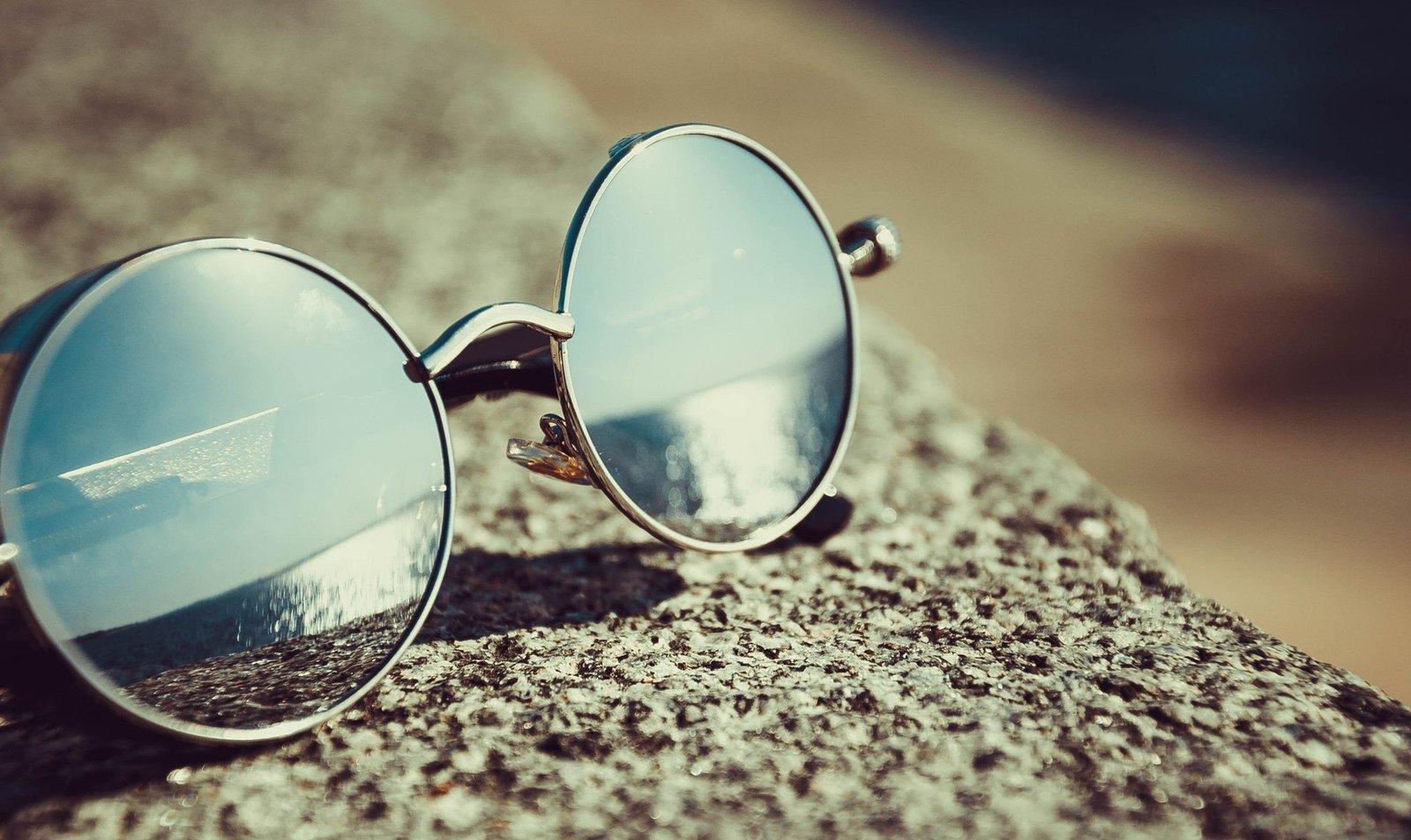 Unbranded round metal sunglasses on stone, illustrating eyewear category expansion for lifestyle brands