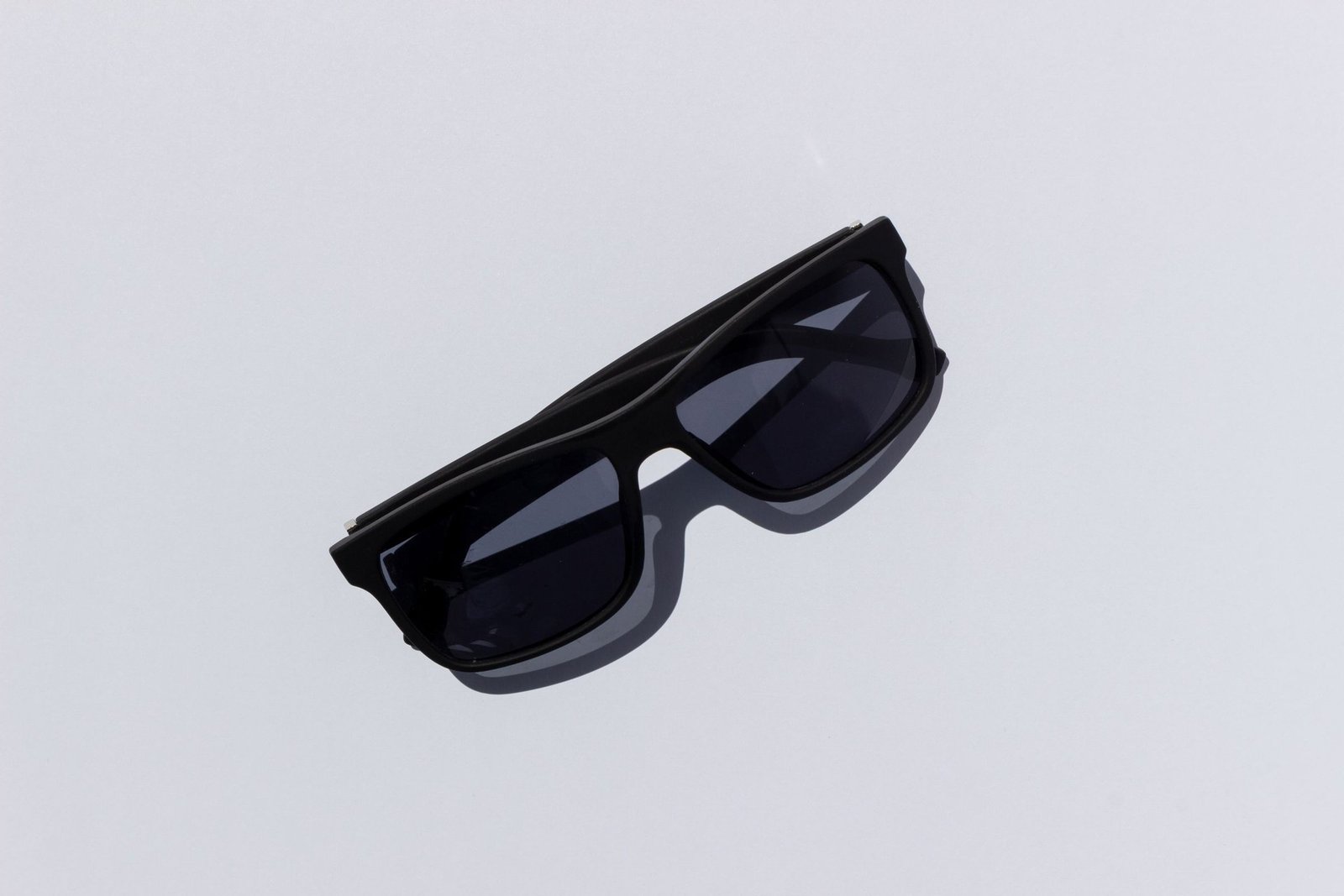 Eyewear compliance standards in-content image – Concept Eyewear Unbranded matte black sunglasses on a pale studio surface, ready for eyewear compliance standards testing