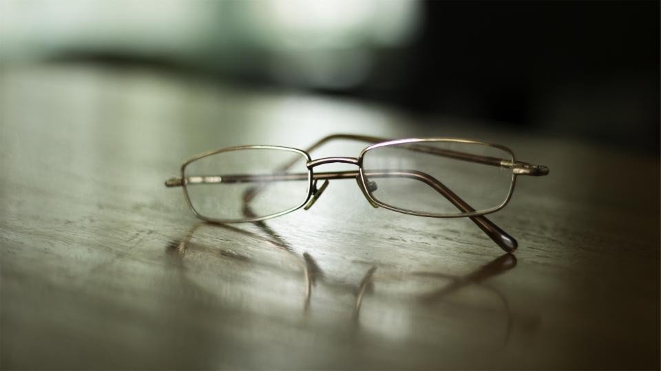 Unbranded thin metal eyeglasses on a wooden table, a sample stage with an eyewear manufacturing partner