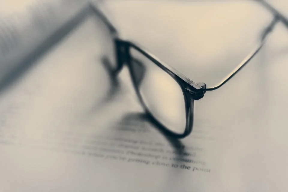 Eyewear OEM RFQ checklist: unbranded eyeglasses resting on a printed tech pack document for sample review