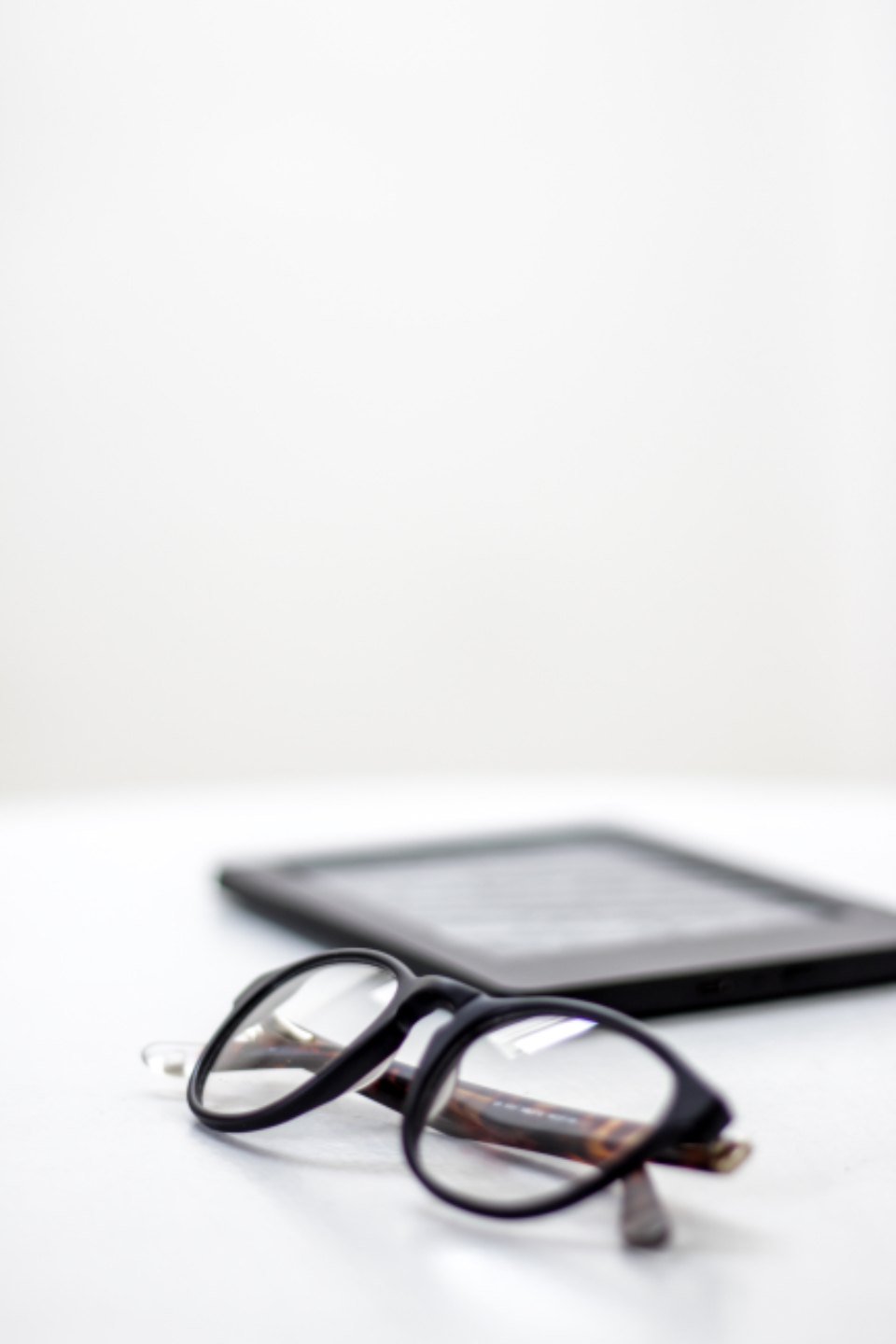 Eyewear OEM sampling checklist featured – Concept Eyewear Eyeglasses with black frames resting on a white desk, with a blurred tablet in the background.