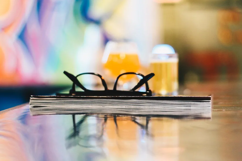 Eyewear OEM sampling checklist in content – Concept Eyewear Unbranded eyeglasses on a magazine at a desk, illustrating an eyewear OEM sampling checklist and tech pack review
