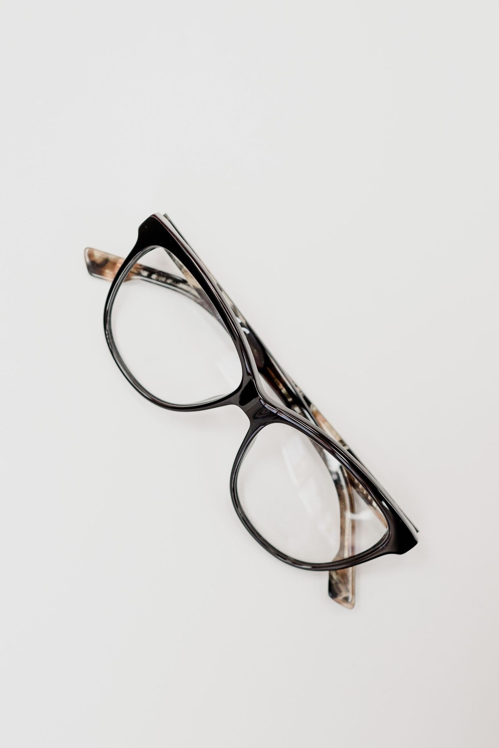 Eyewear premiumisation US: unbranded dark cat-eye optical frames on white surface, no logos